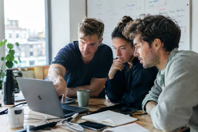 Three founders working through something together on a laptop